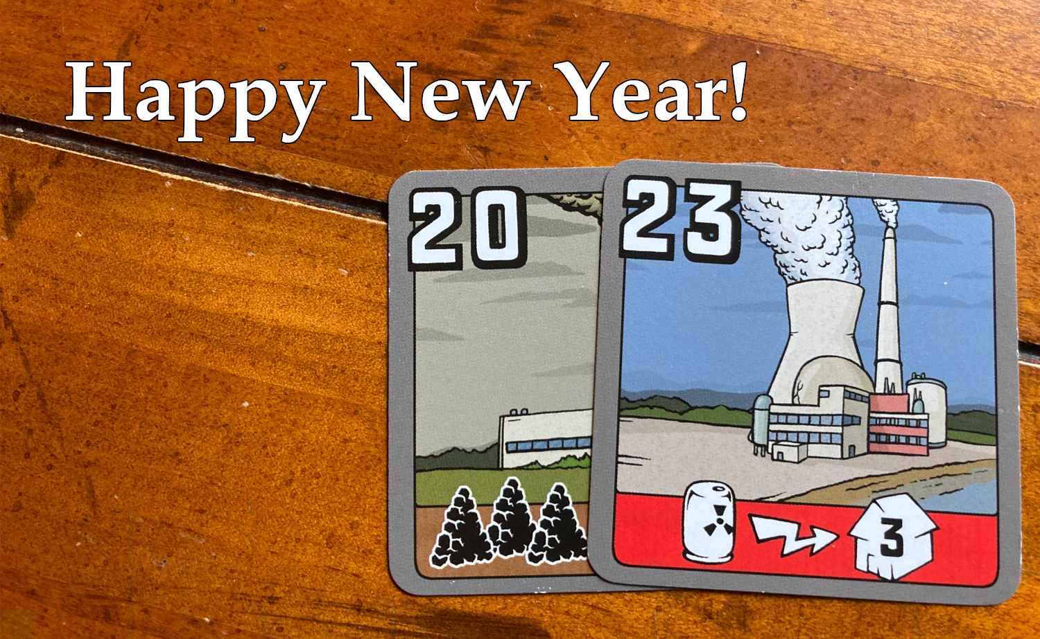 Happy New Year text with picture of two power plants from the game Power Grid that are 20 and 23 numbers